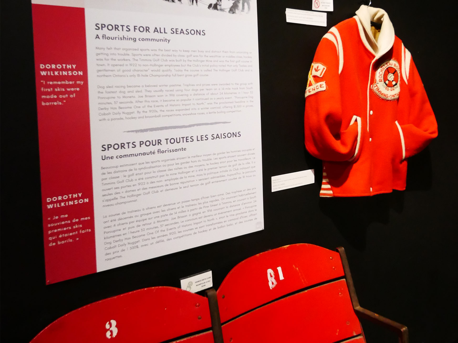 An antique jacket from a local Timmins sports team next to an interpretive plaque about the history of sports in the area, found at the Timmins Museum. 