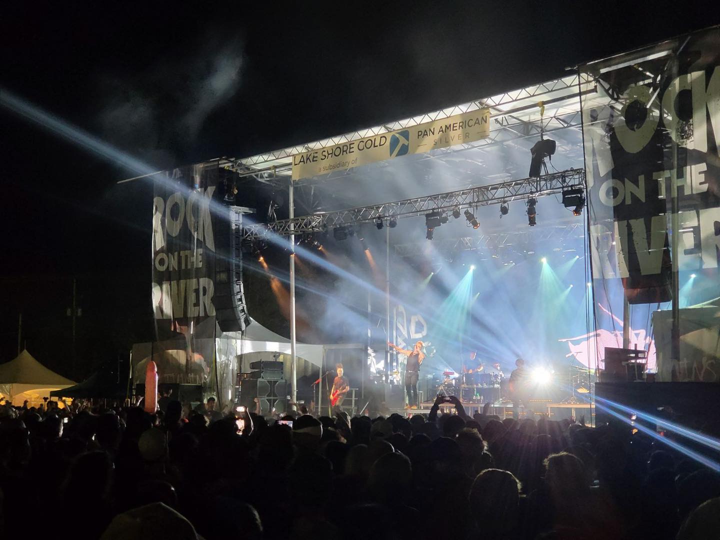 A concert showing a man on an outdoor stage singing at night. 