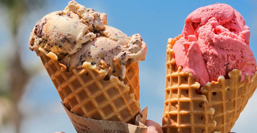 Two ice cream cones against a blue sky.