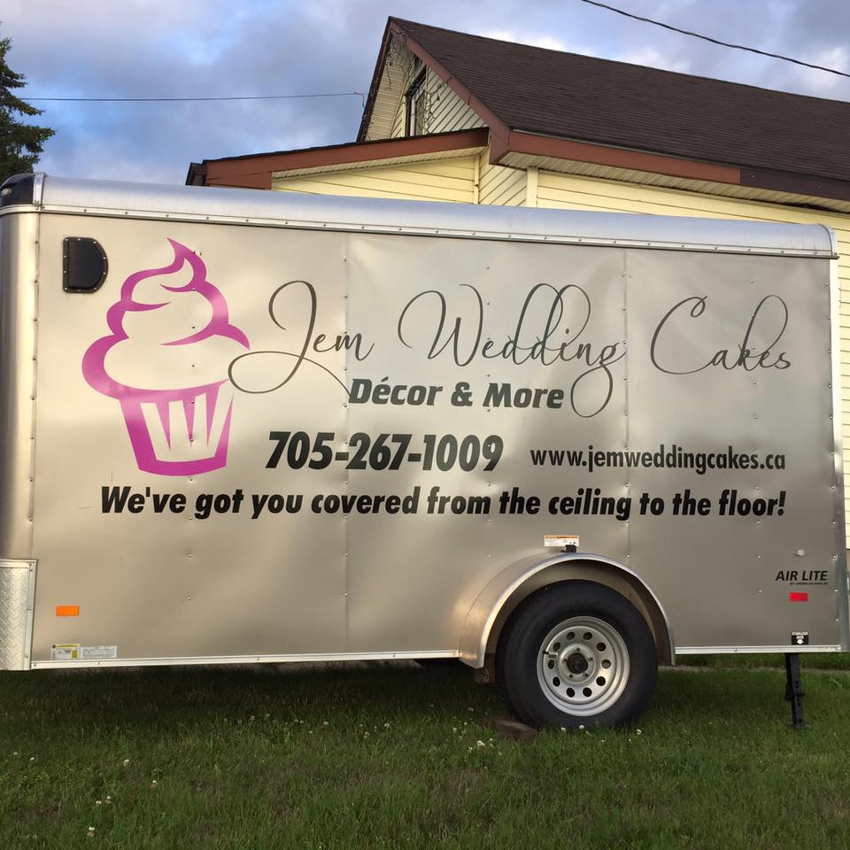 A Close up of the side of the Jem Wedding Cakes Decor & More truck which has the logo of the bakery including the contact information and their slogan which is We've got you covered from the ceiling to the floor!