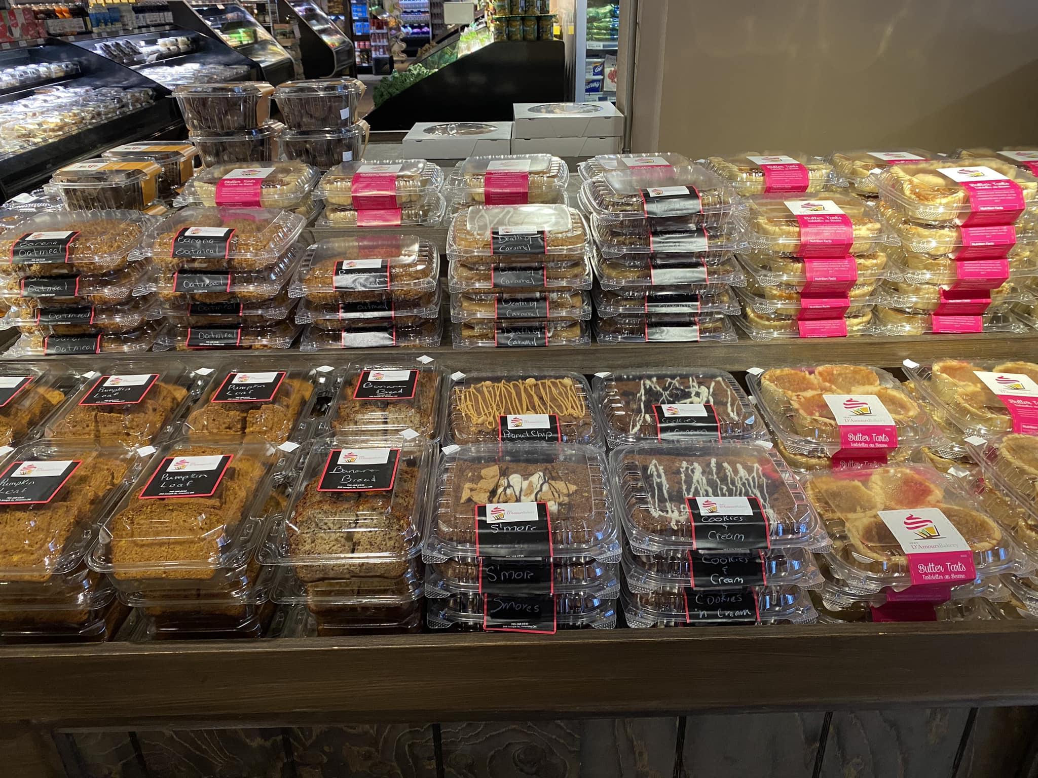 A view of an assortment of pastries that are boxed with D'Amours Bakery logo on top of a shelf and stacked on top of each other