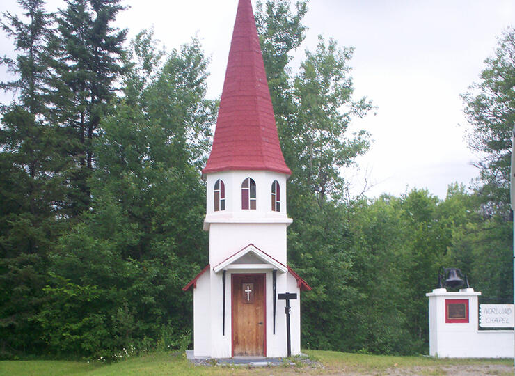 Small white building with small tower and red pointed roof. 