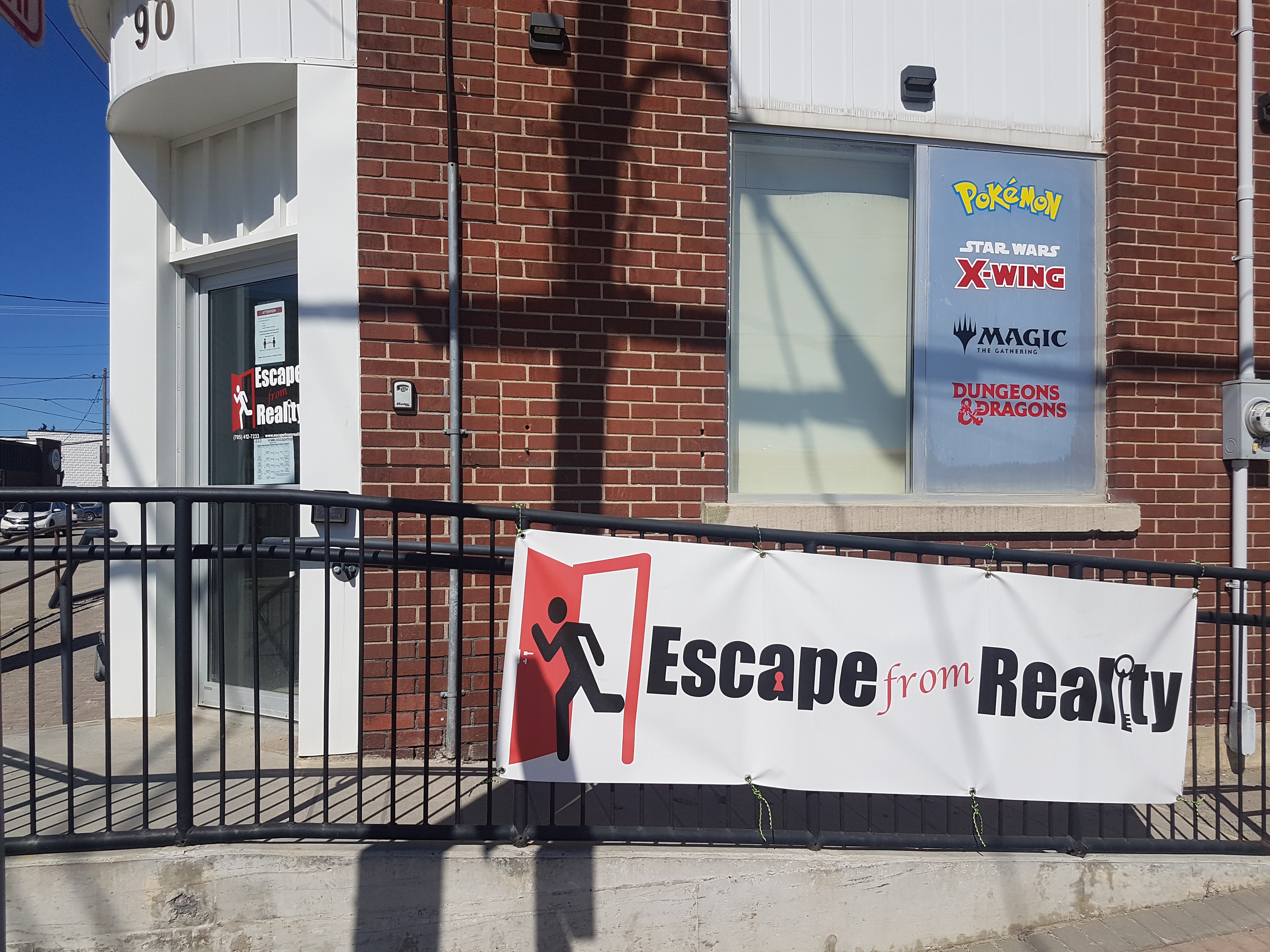 A close-up of the Escape from Reality storefront featuring a banner of the businesses' logo that is hung from the staircase