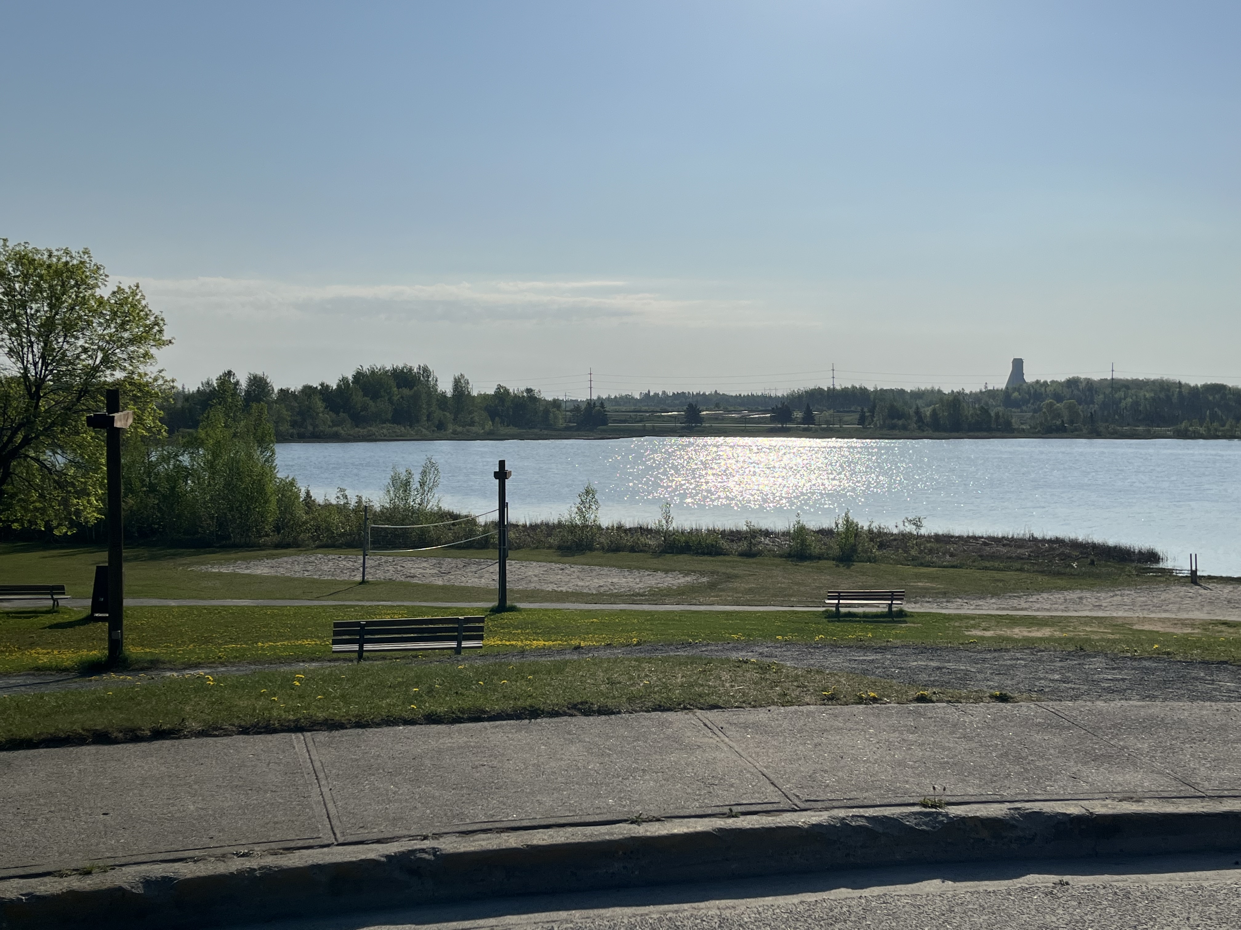 a landscape view of Gillies Lake with the McIntyre Headframe in the background and trees on the left hand side