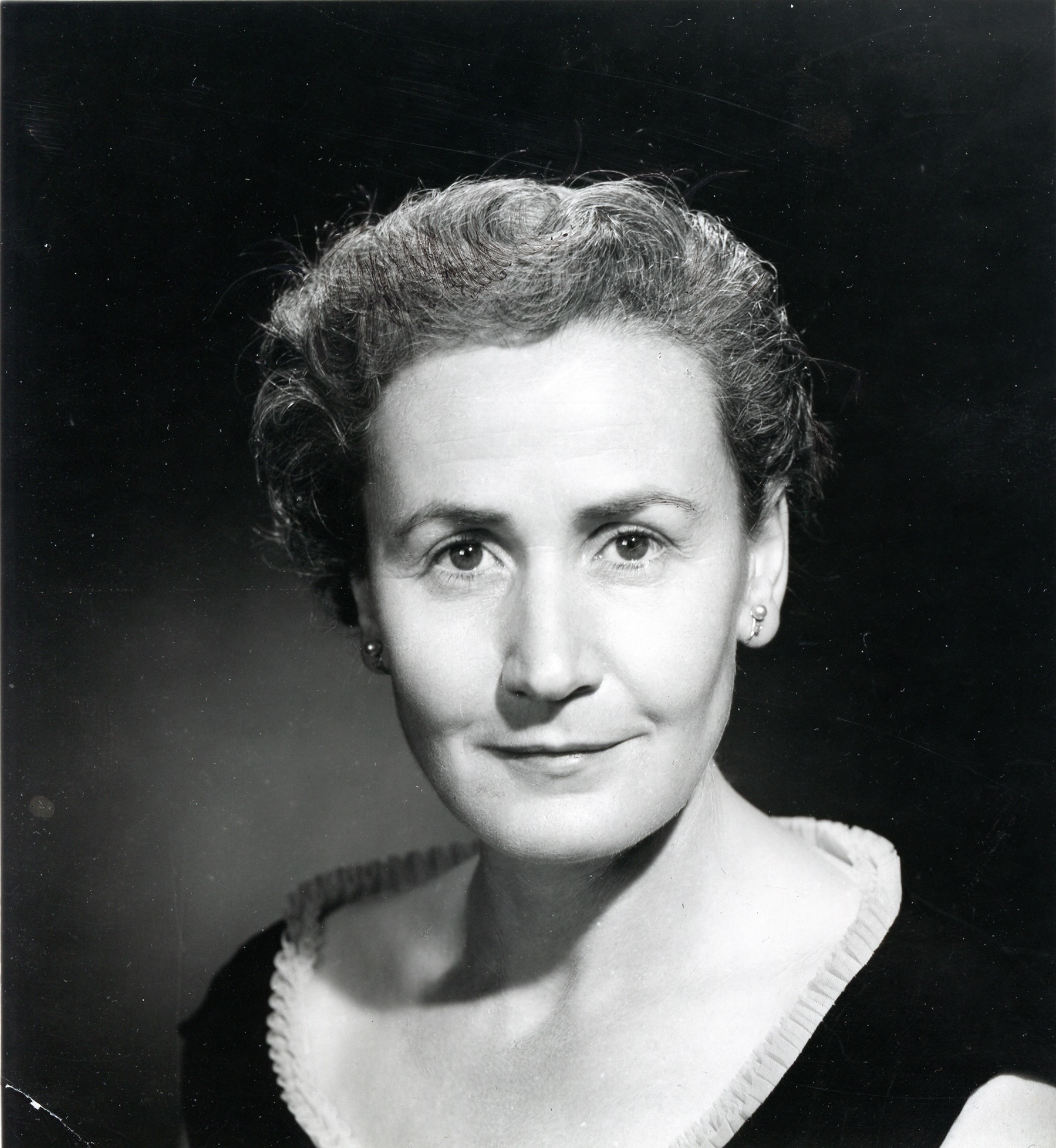 a black and white photograph of a young Sheila Burnford, smartly dressed in a stylish black gown with her hair set.