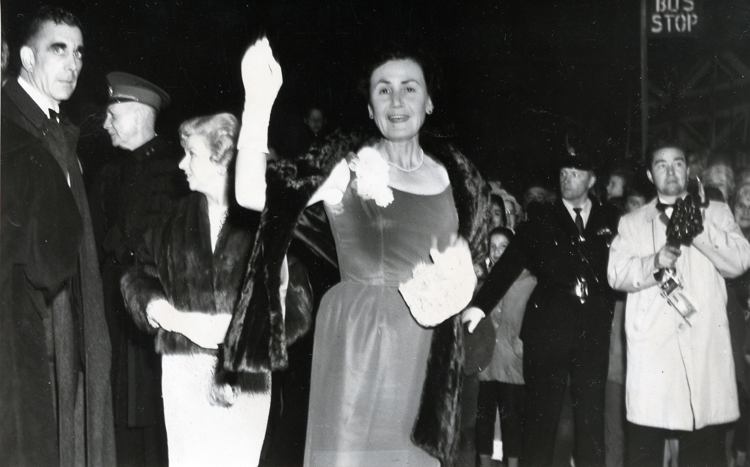 Famous author Sheila Burnford waving and smiling in an elegant gown and fur shawl on her way into the Port Arthur 1963 world premiere of the Walt Disney movie The Incredible Journey, based off her book.