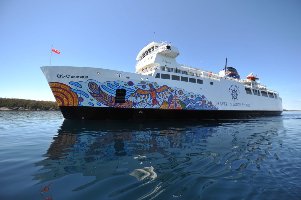 The MS Chi Cheemaun; a large ferry with its bow painted with a brightly coloured mural of birds on a swirling blue background. 