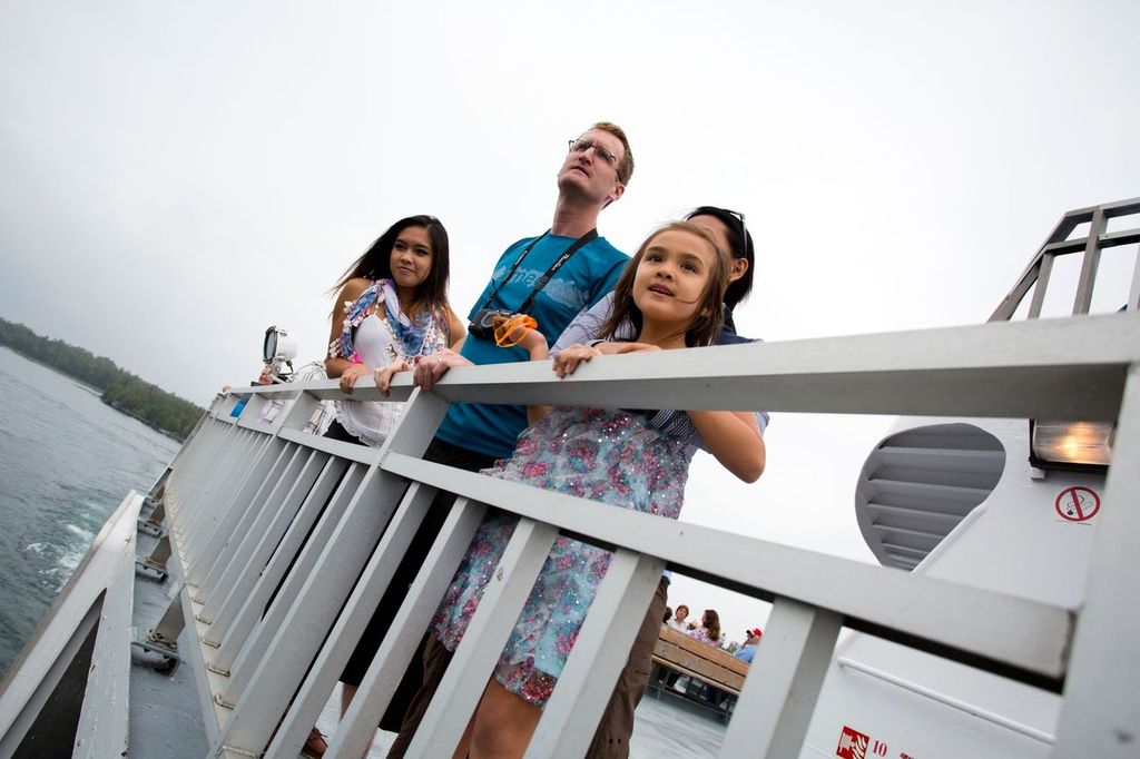 a family looks eagerly into the distance over the rail of the MS Chi Cheemaun 