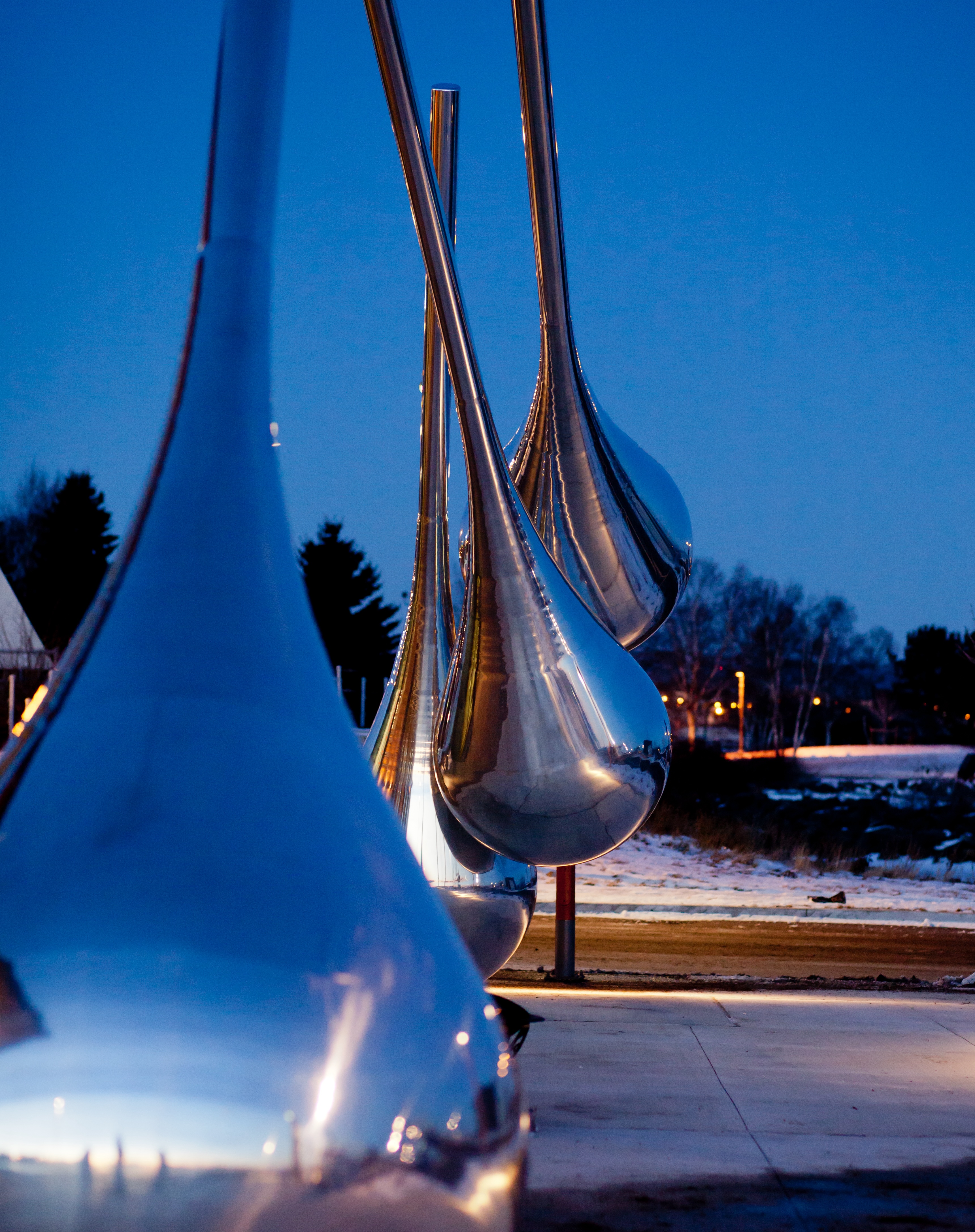 "Traveller's Return", an outdoor sculpture in Thunder Bay; large mirror-like metal water droplets displayed near the waterfront.