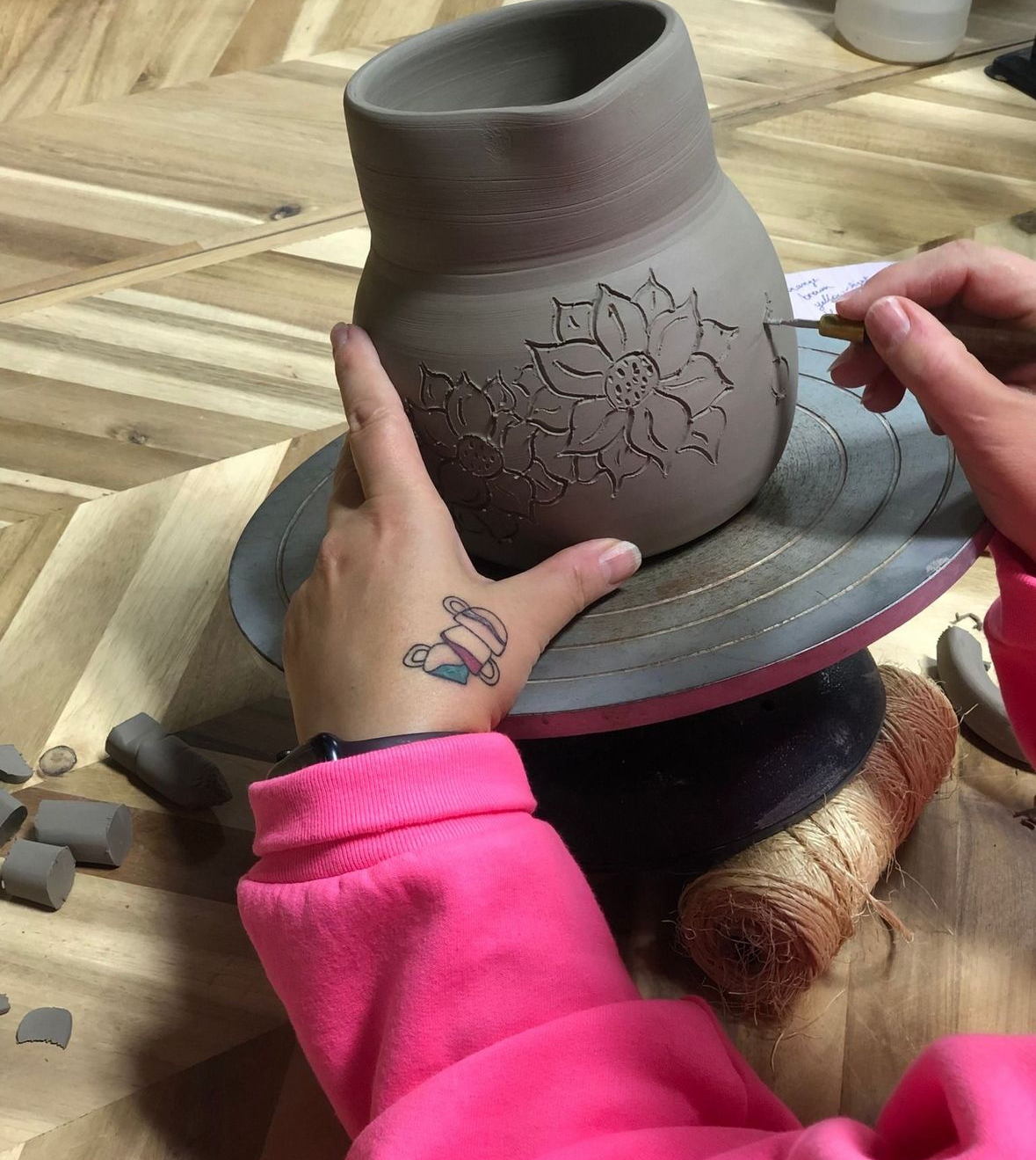 An individual carving a piece of pottery