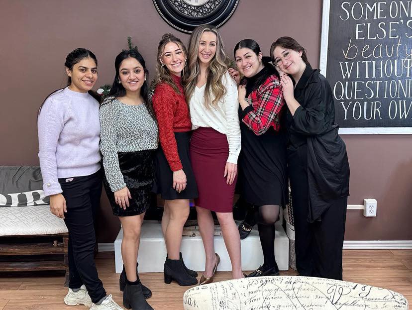 the staff are photographed together in a line and have one of their hands on each others shoulder. They are dressed in red, black, white and gray inside of their store