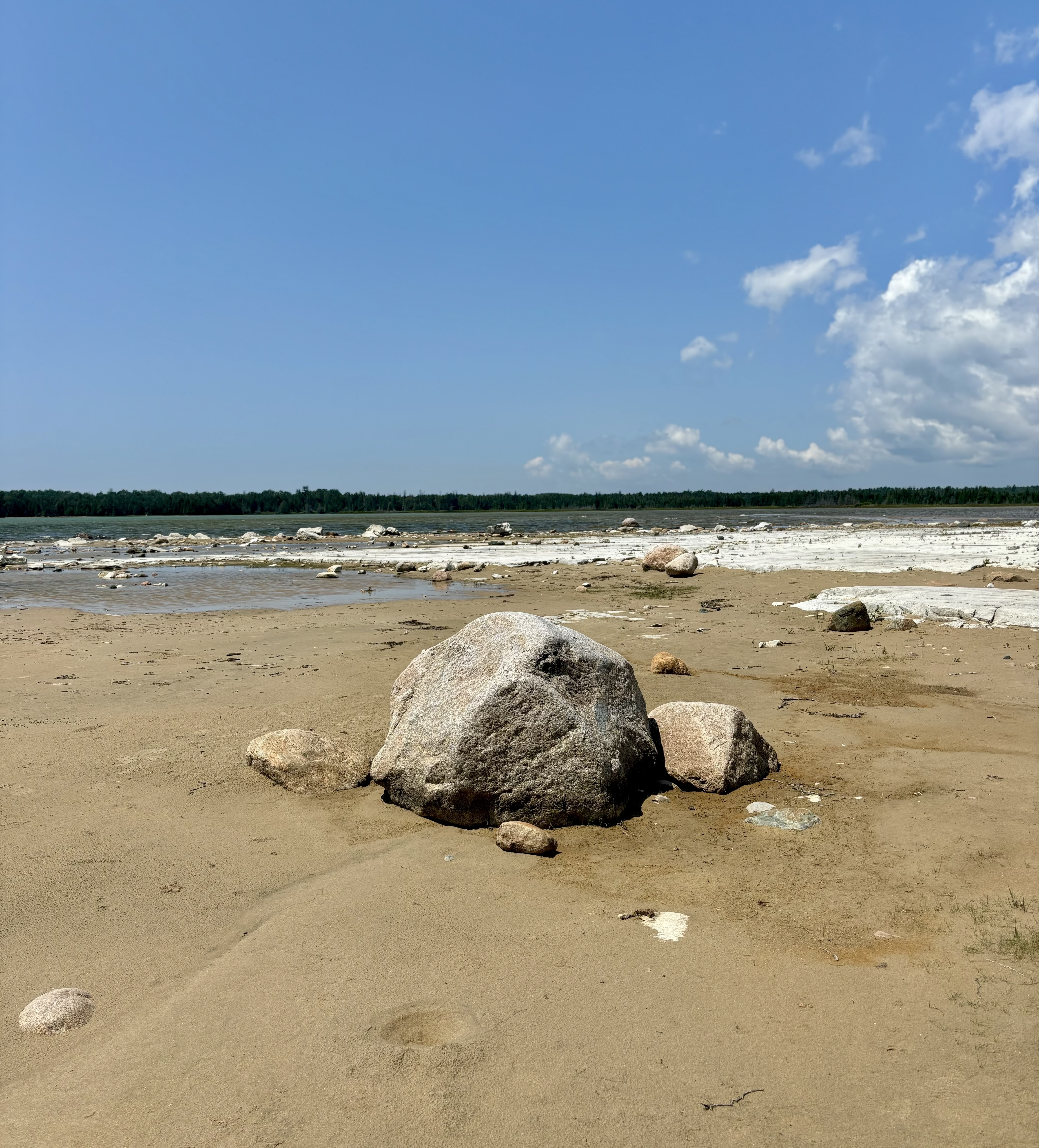 Misery Bay; a bolder on a sandy beach under a bright blue sky.