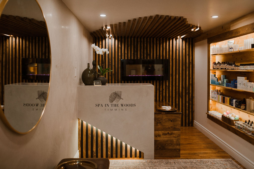 the reception desk is in the center of the image with a round mirror on the left-hand side and a display case full of products on the right