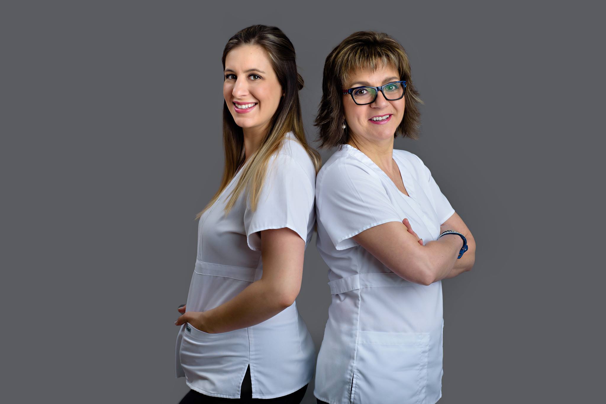 the owner on the right-hand side and an employee standing side by side wearing white shirts in front of a gray background