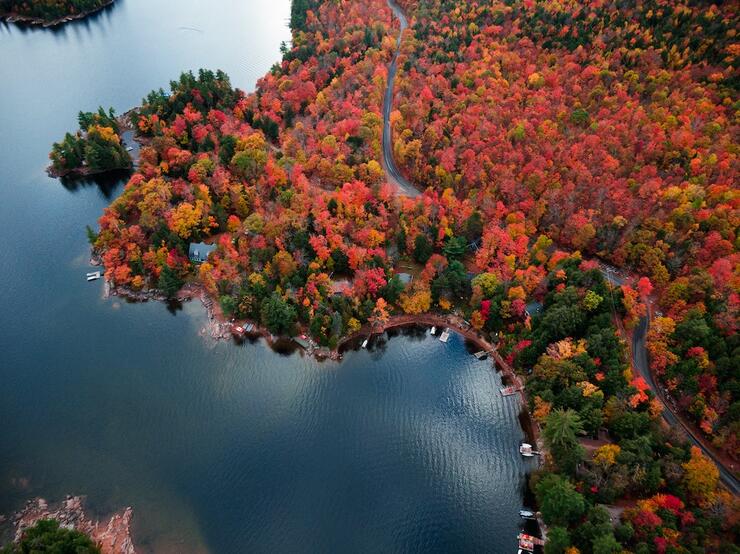 a glassy lake surrounded with bright red, yellow and green autumn forest. 