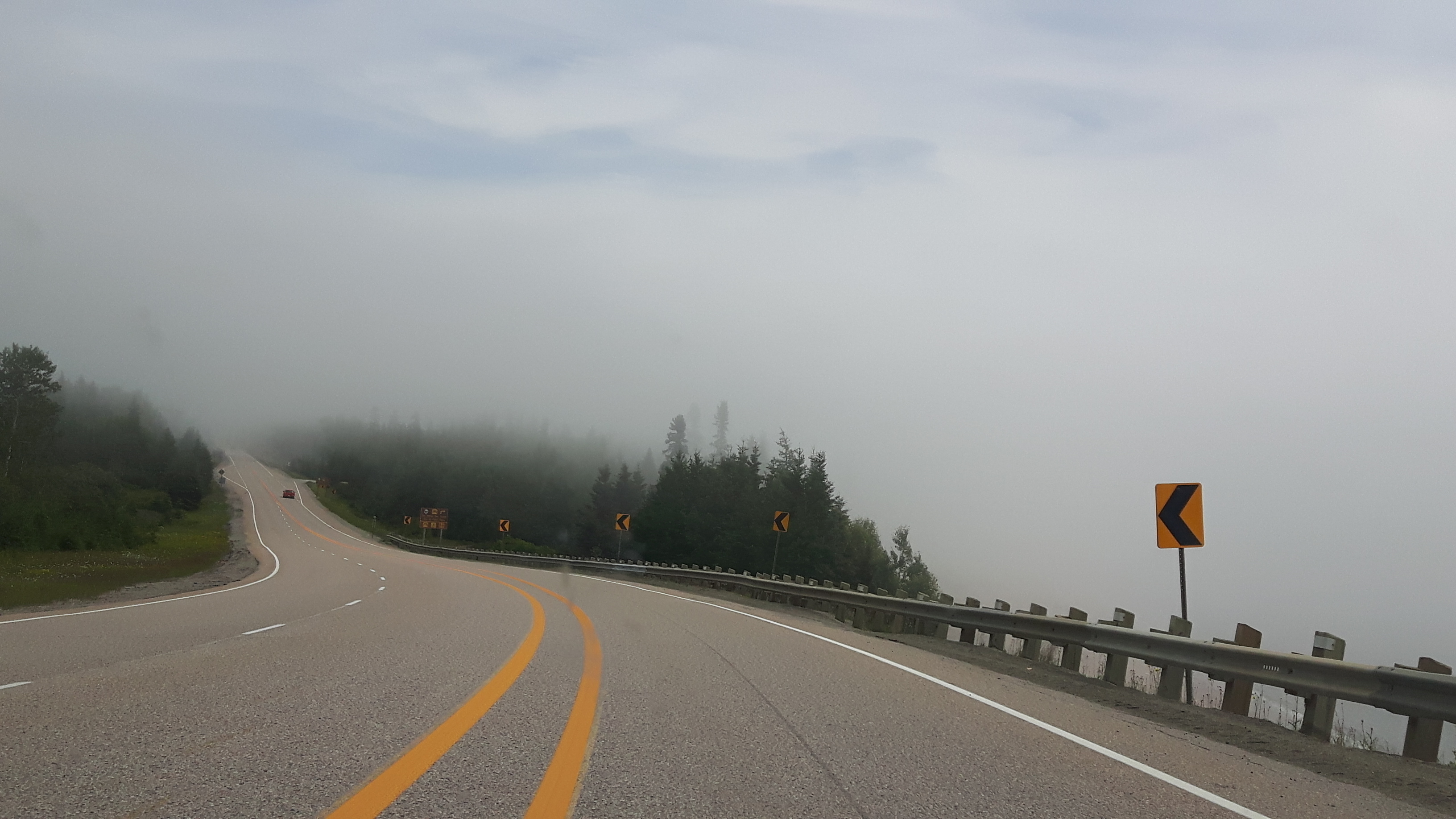 a stretch of the paved Highway 17 in Ontario, surrounded in boreal forest and moody grey fog.