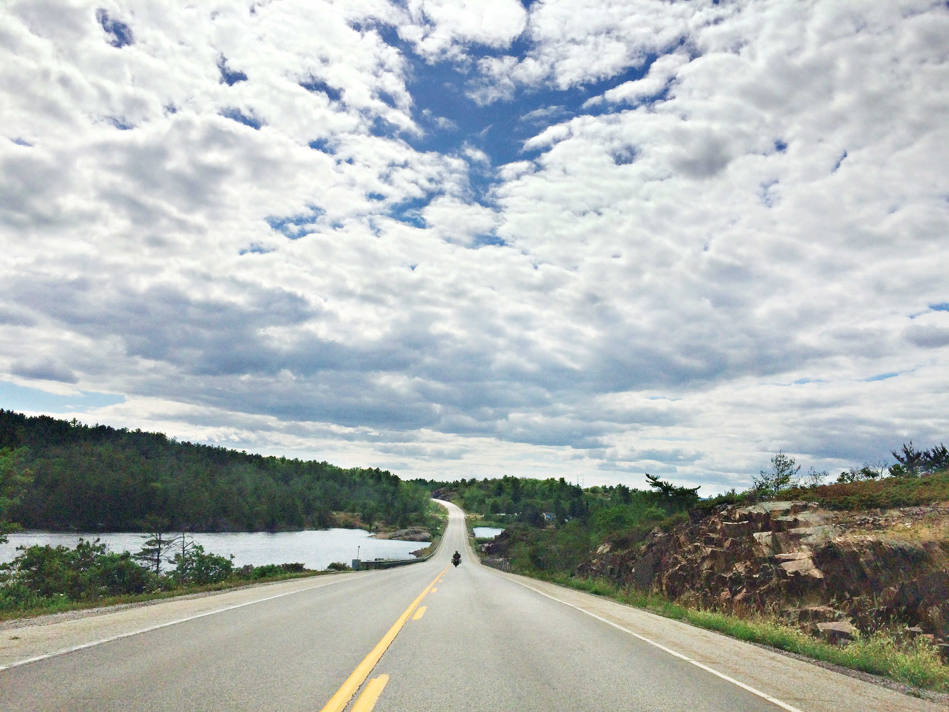 a stretch of paved Ontario Highway 6 extending to the horizon, with lakes and forest on either side.