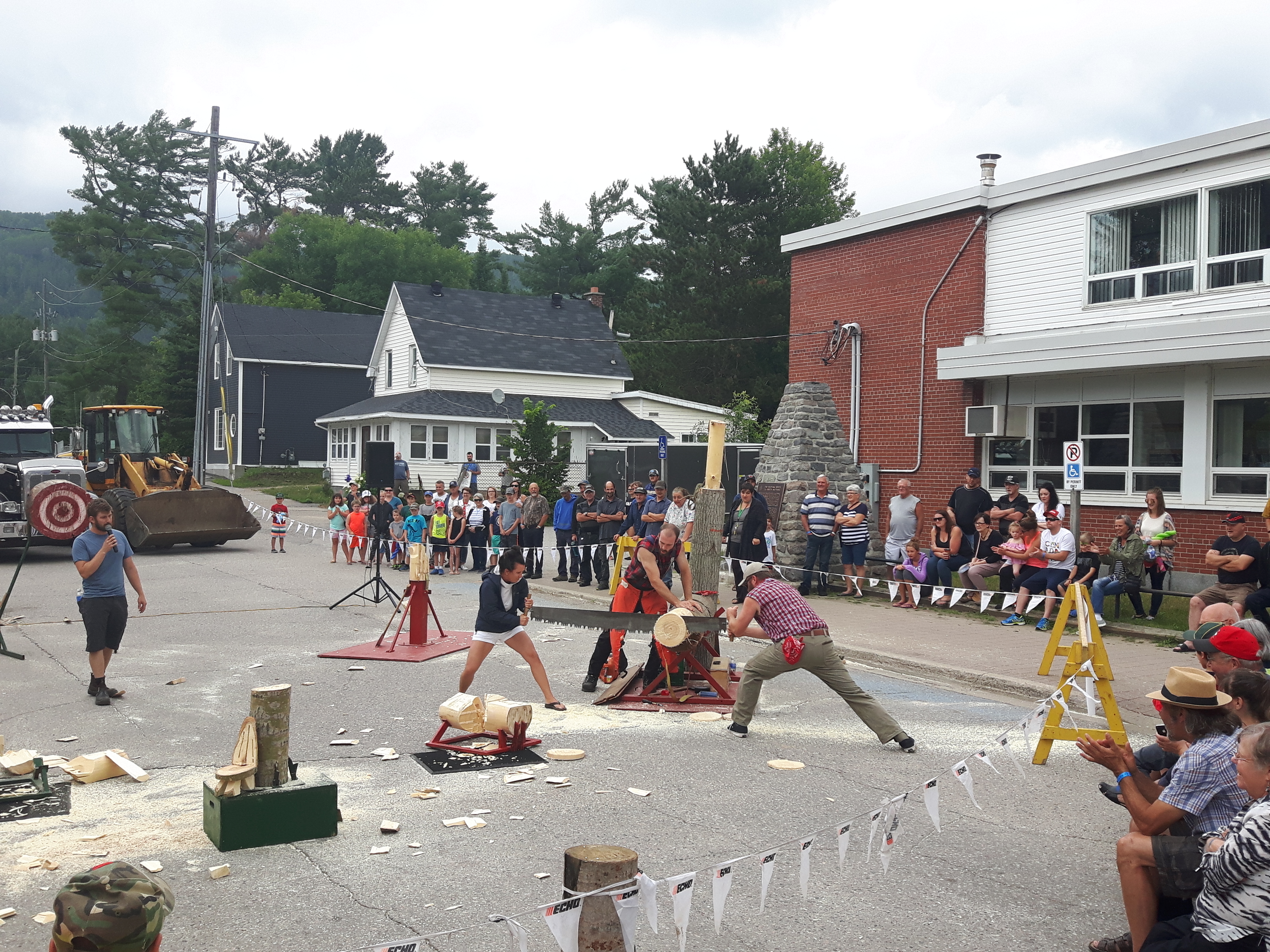 log sawing competitions in a square in Mattawa, with a crowd standing around watching.