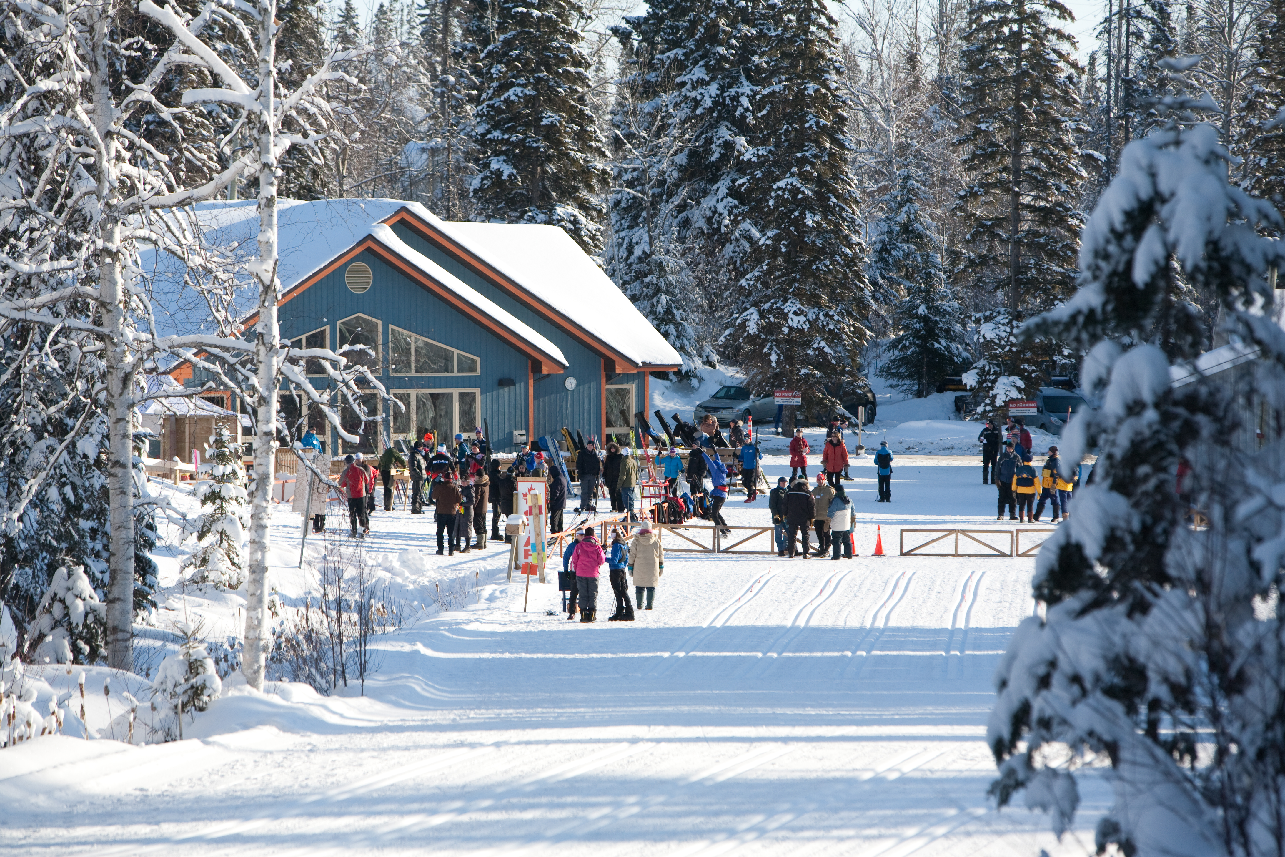 Porcupine Runners Ski lodge on a snowy day, with skiiers crowded around it, walking and chatting with their ski gear in hand.  