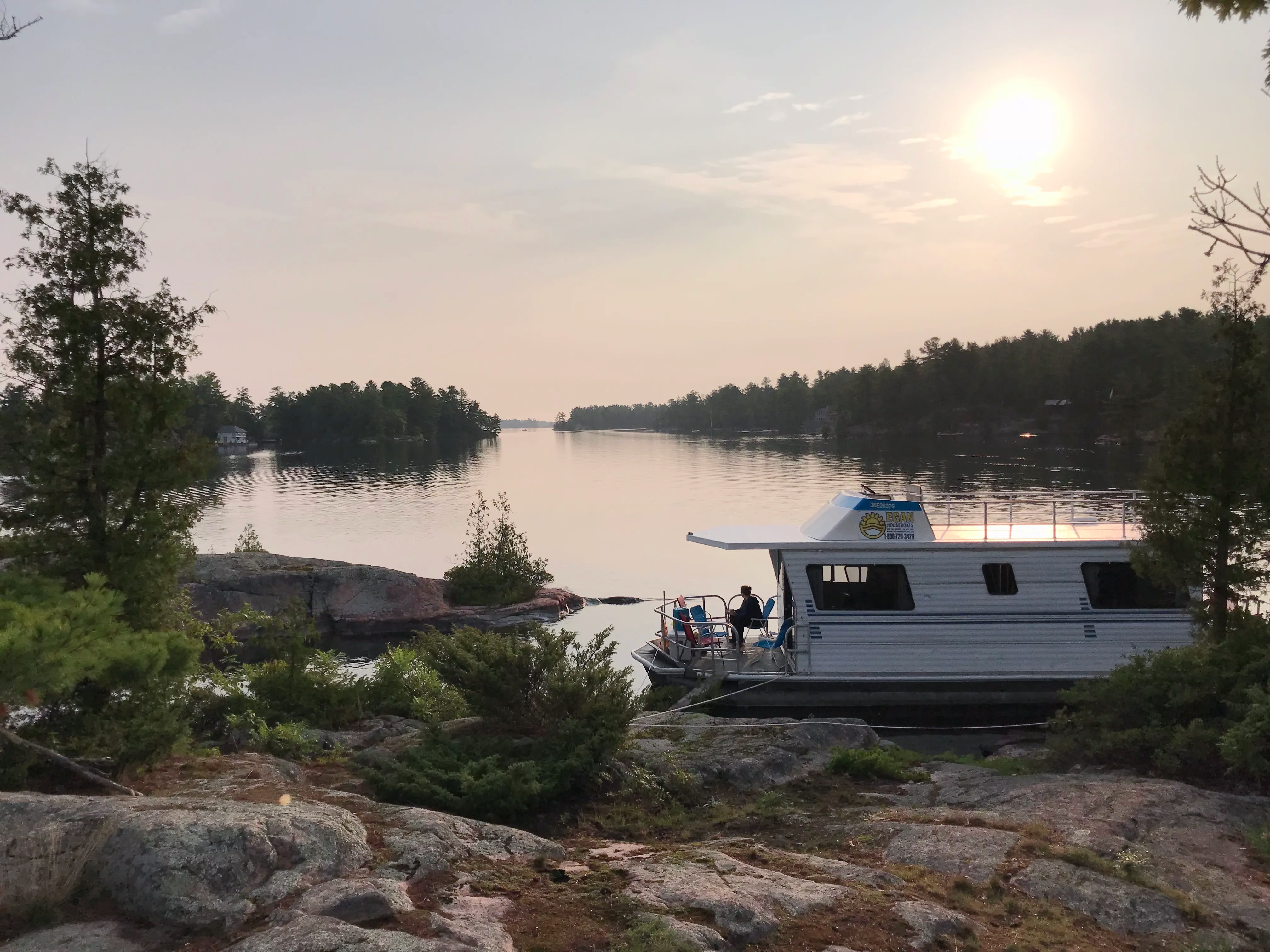 houseboat next to beautiful rocky shore at sunset