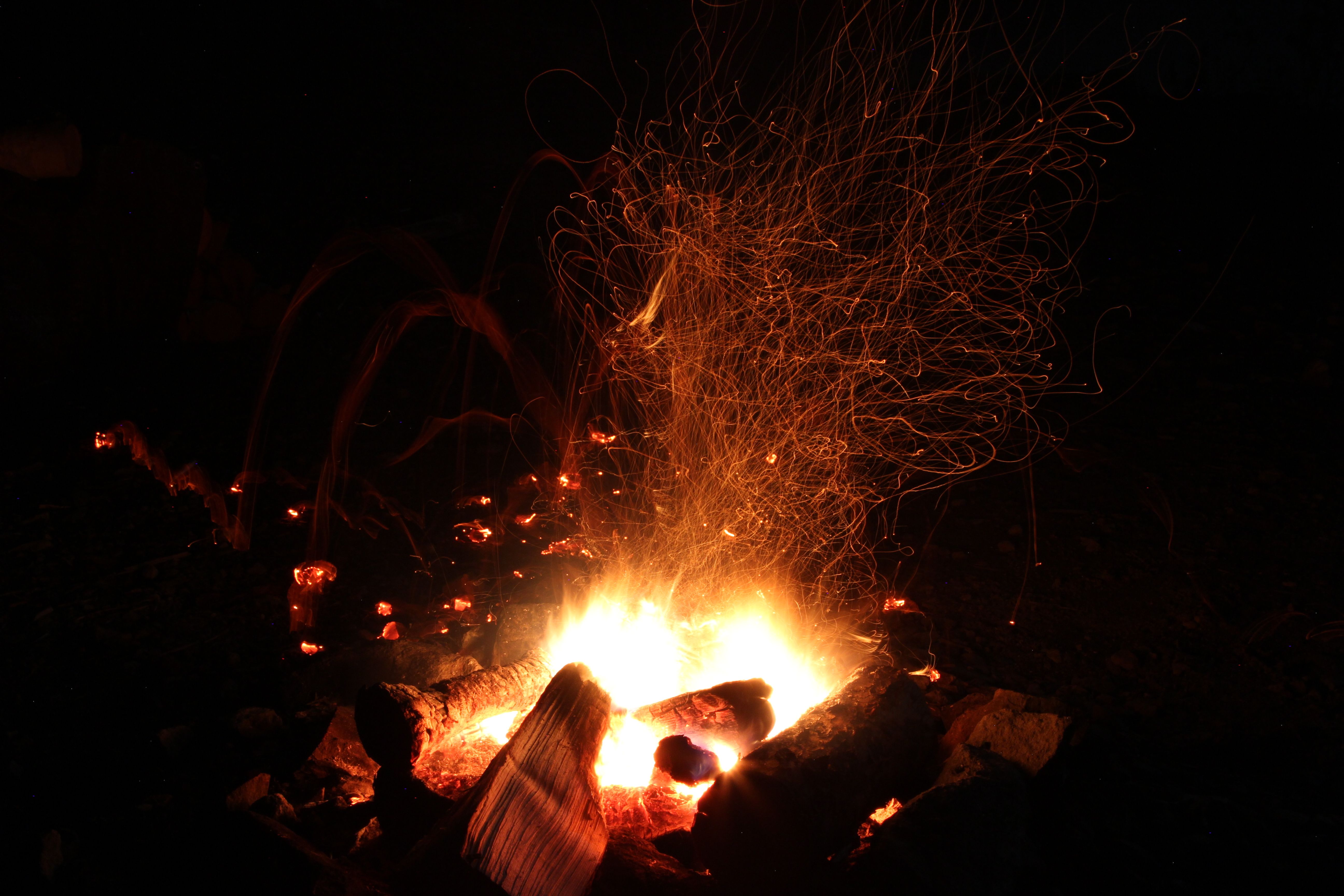 orange sparks spraying up around a campfire glowing in the dark