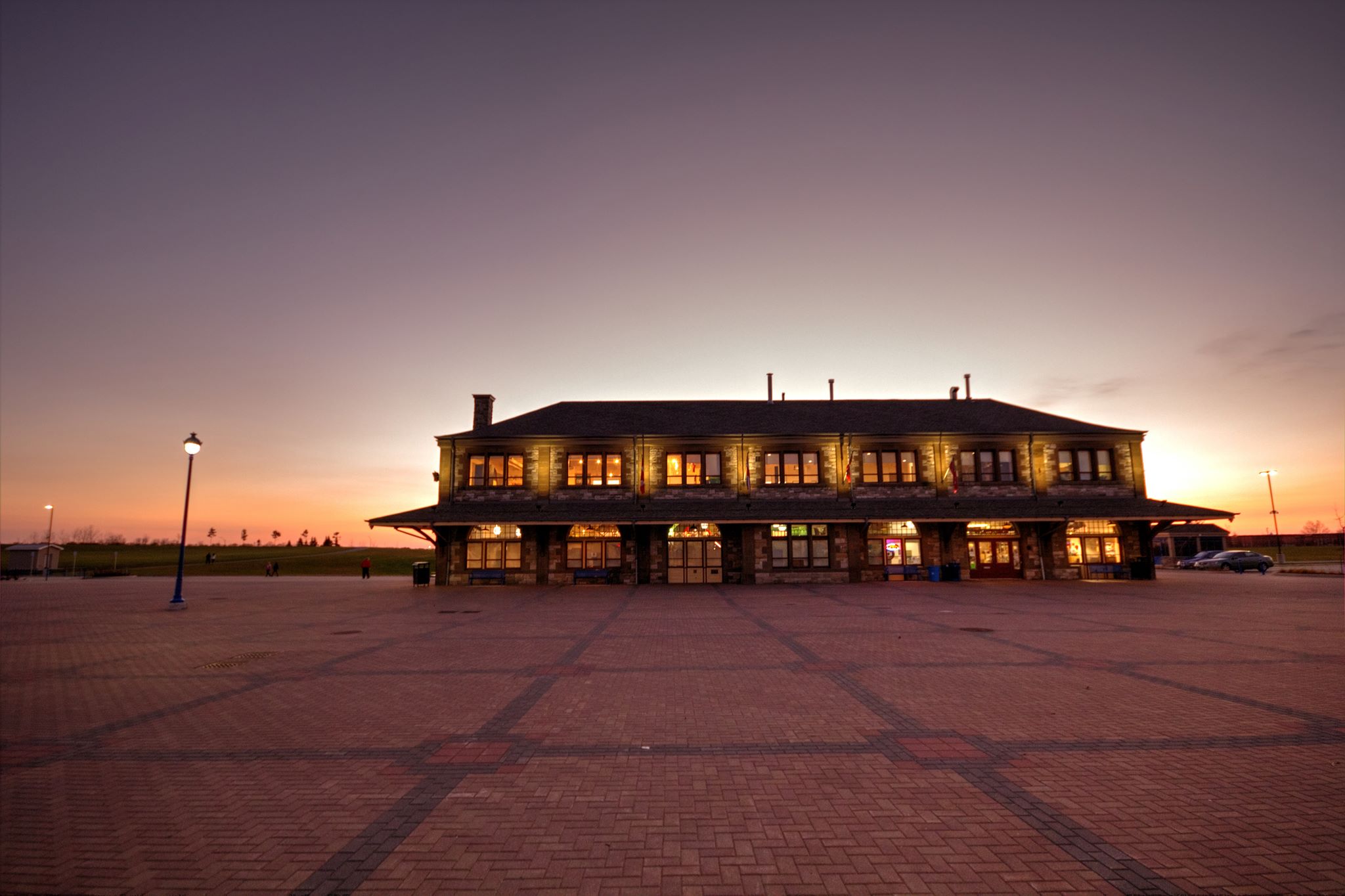 The North Bay Museum; an antique mansion with illuminated window in front of a setting sun. 