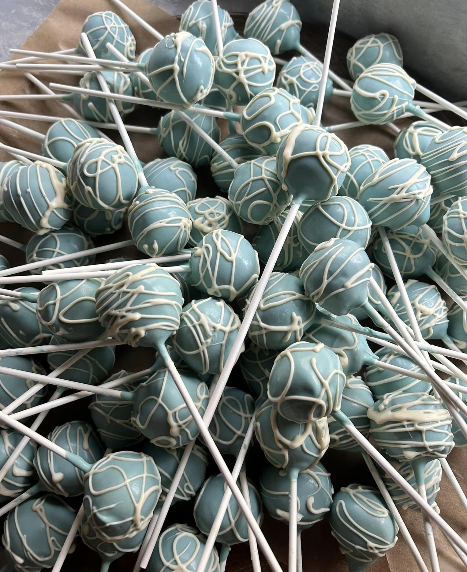 cake pops coated in baby blue and white chocolate stacked high on a wooden table