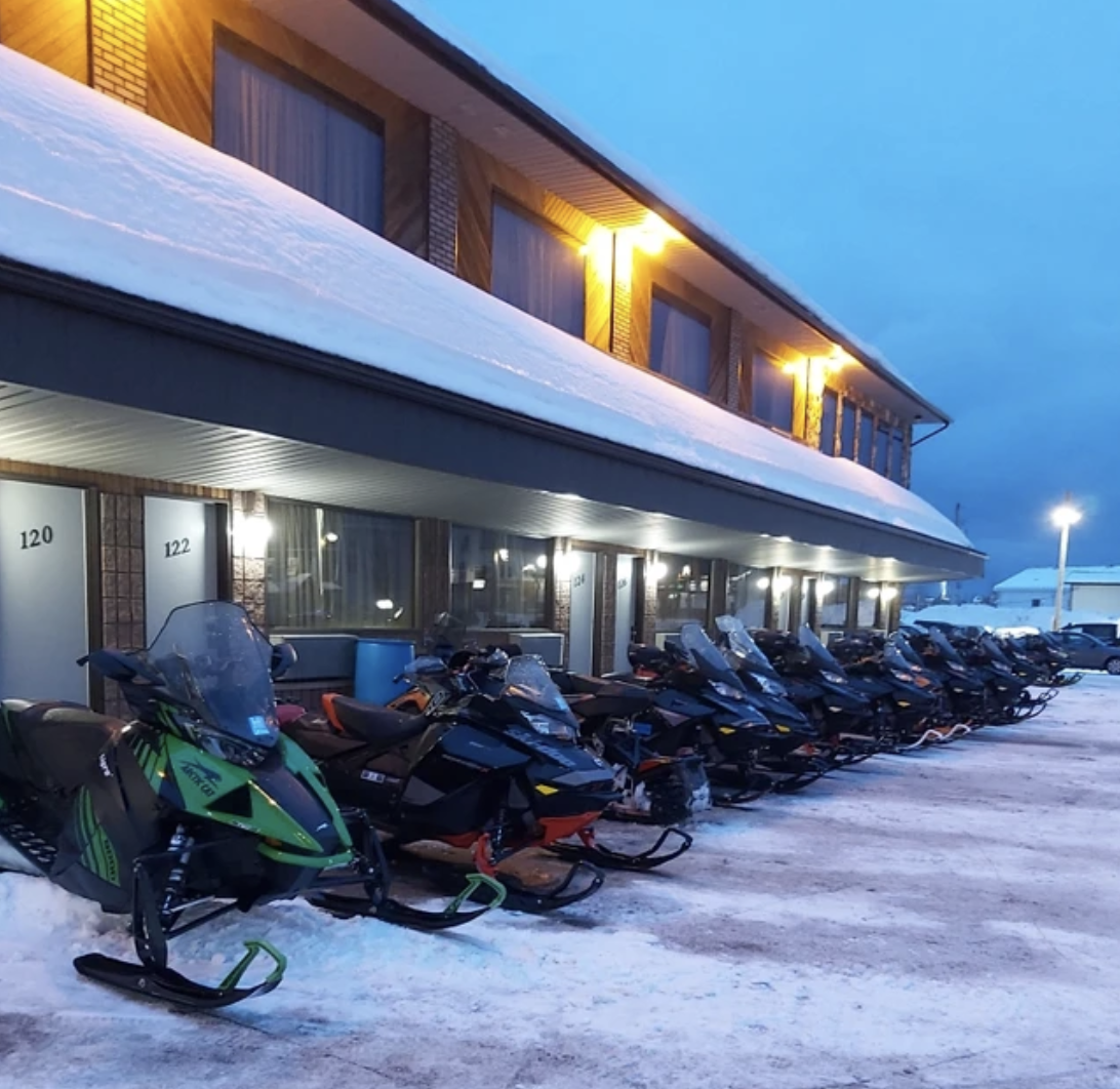 Snowmobiles parked in a line outside a hotel in Hearst Ontario.