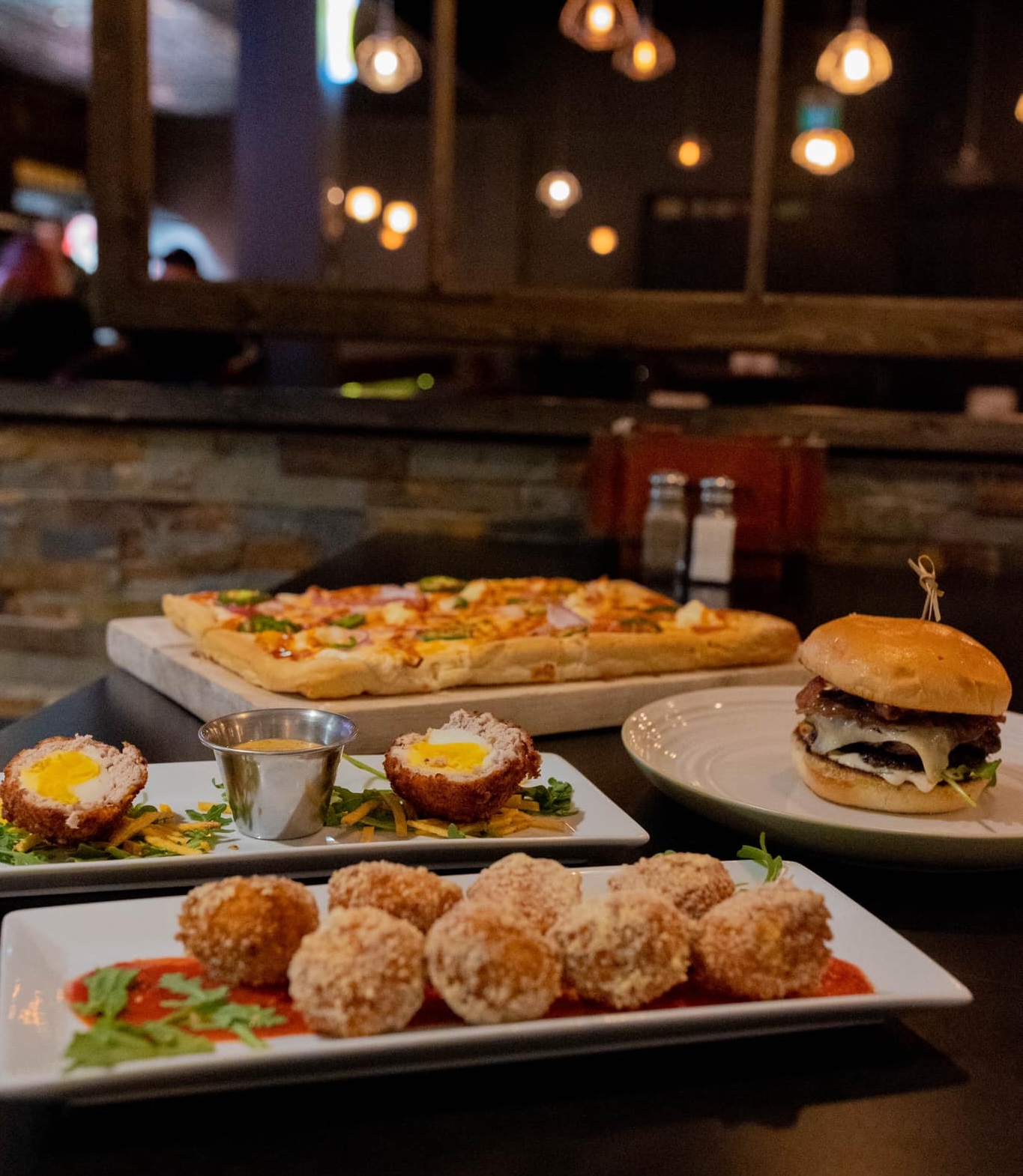 plates of delicious appetizers laid out on a table at the Daventry. The lights are low and there are tables of people visiting in the background. 