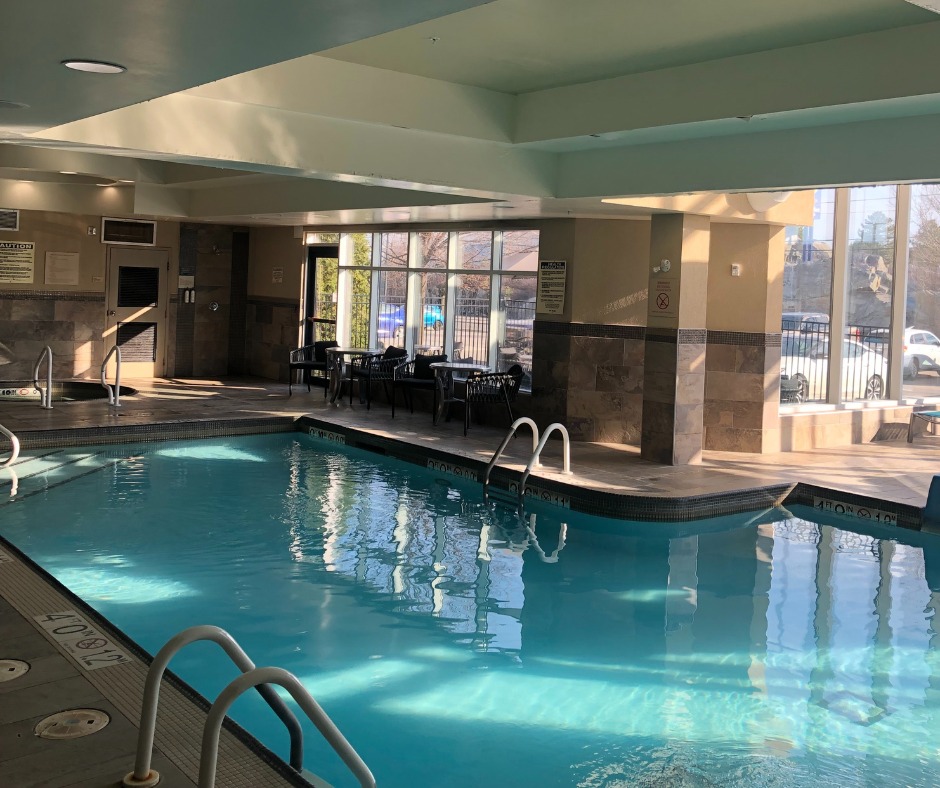 A large, sunny indoor pool surrounded by windows at TownePlace Suites Sudbury.