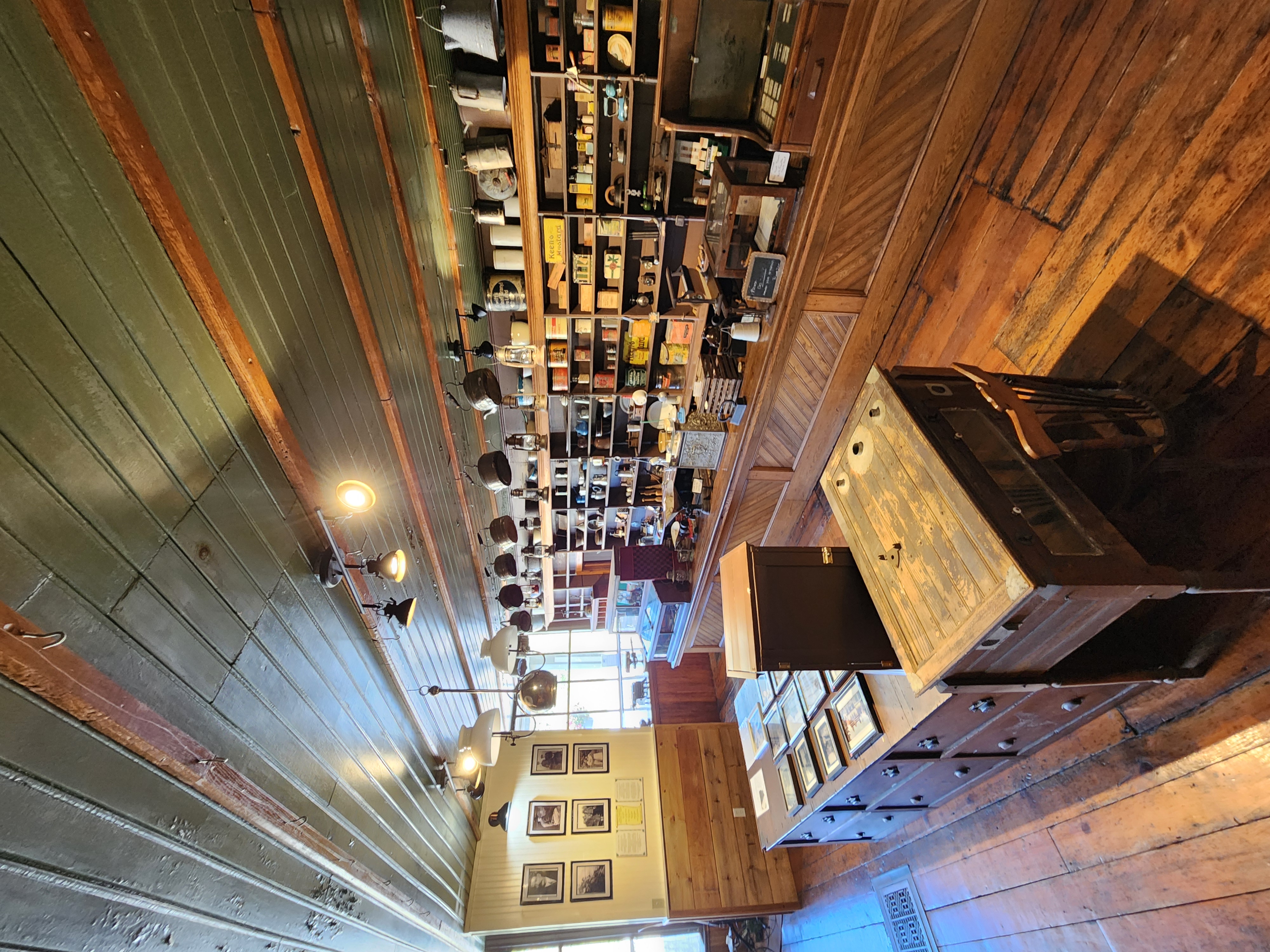 The inside of the Commanda General Store Museum, a dim room with wooden floors, counters and shelves lined with antique grocery items. 