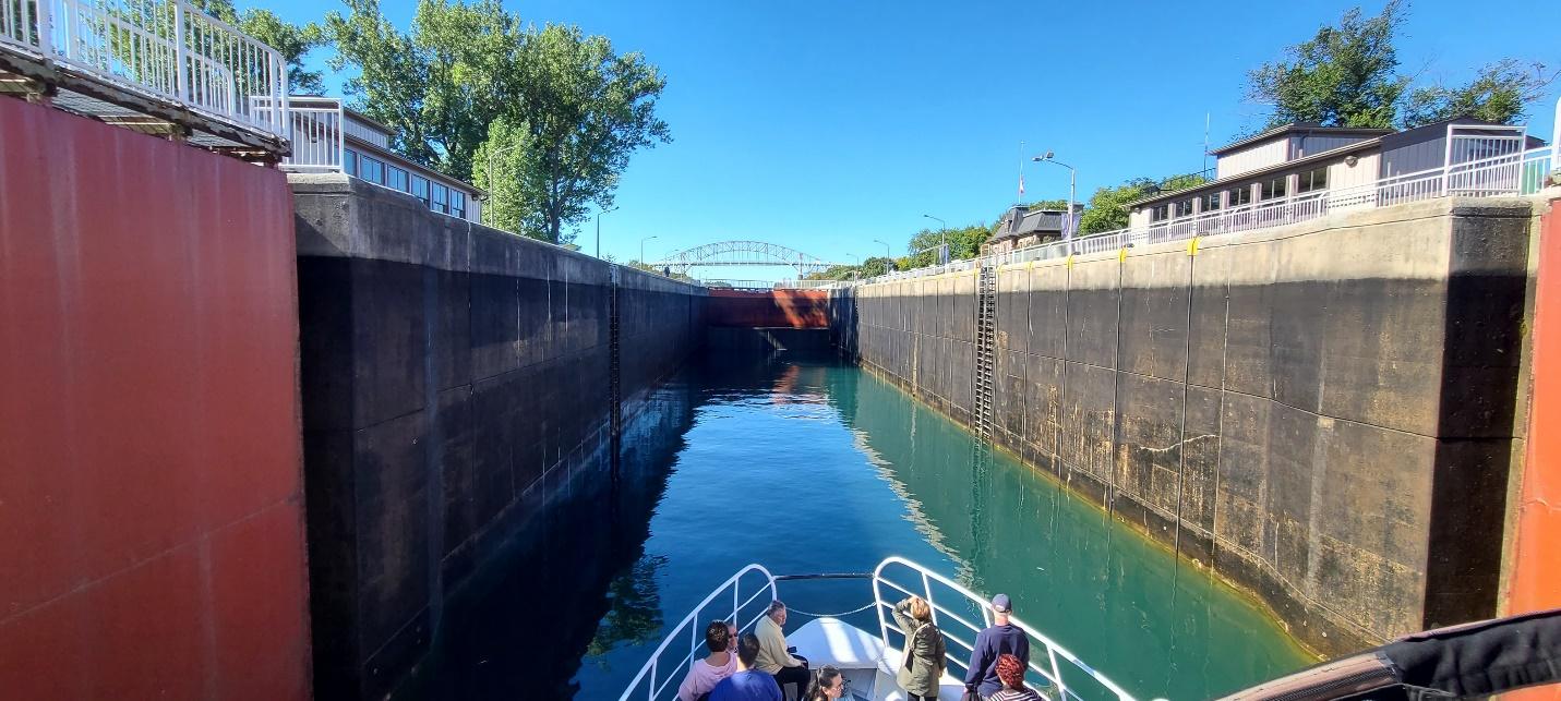 A boat full of people in the Sault Ste. Marie Locks on a sunny day, with the lock half-empty.