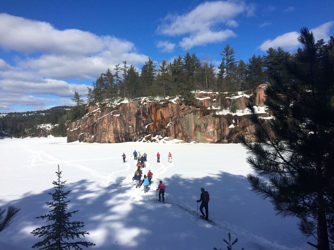 A northern landscape covered in snow with some people skiing. 