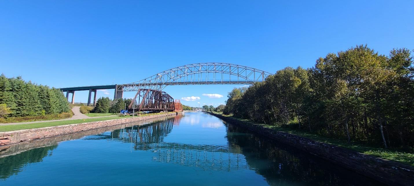 The International Bridge and Emergency Swing Bridge on the St. Marys River under a bright blue sky.