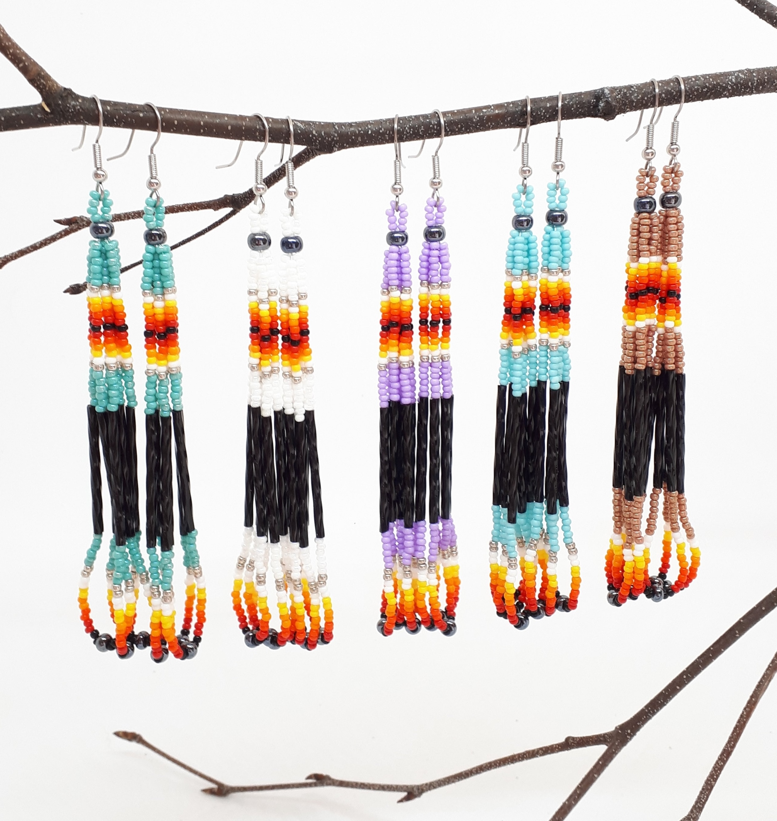 a variety of handmade beaded earrings hanging on a branch