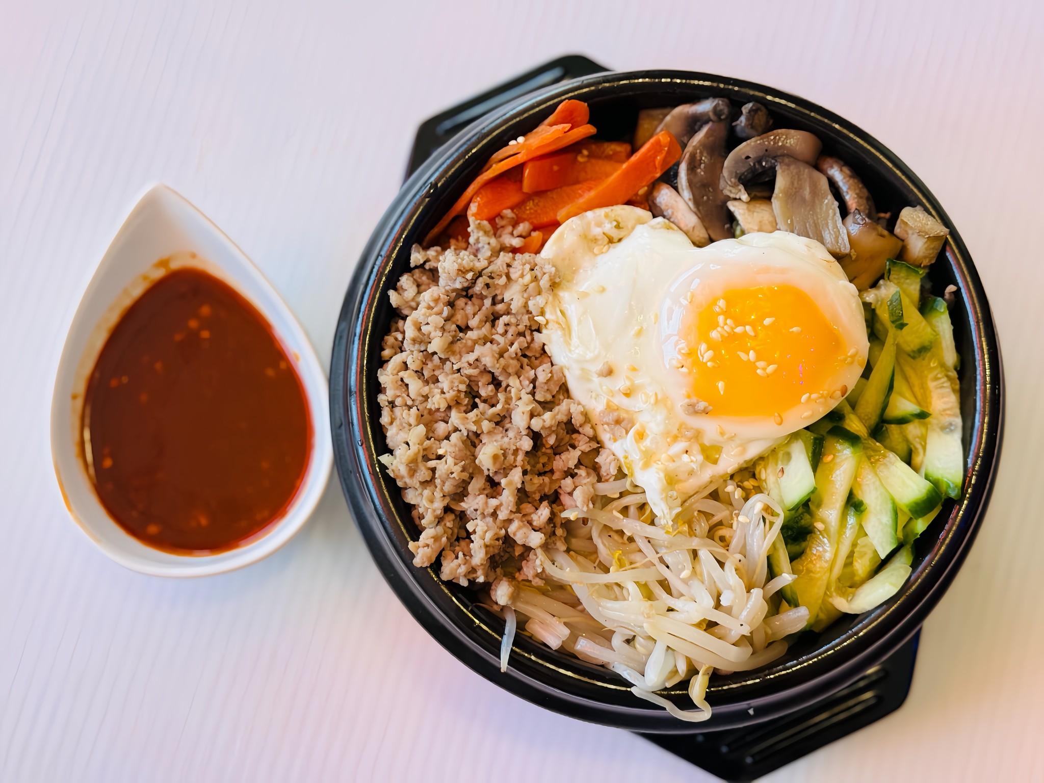 a bowl of bibimbap with the egg on top shaped like a heart.