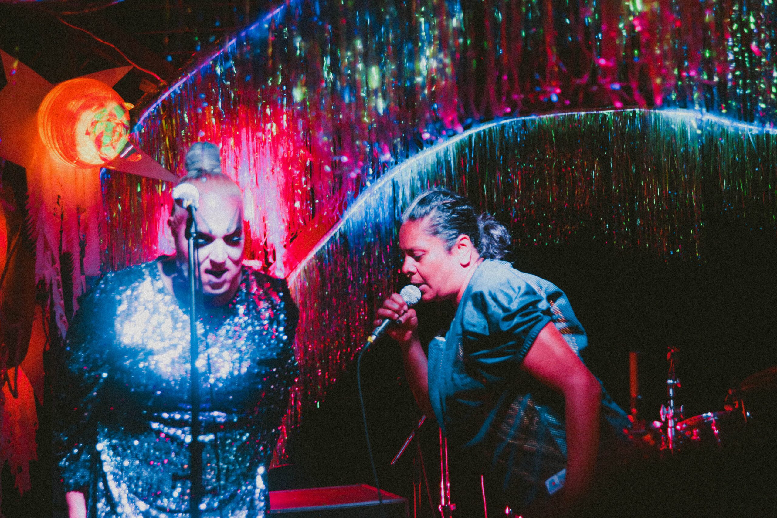 Two performers at night on stage singing. 