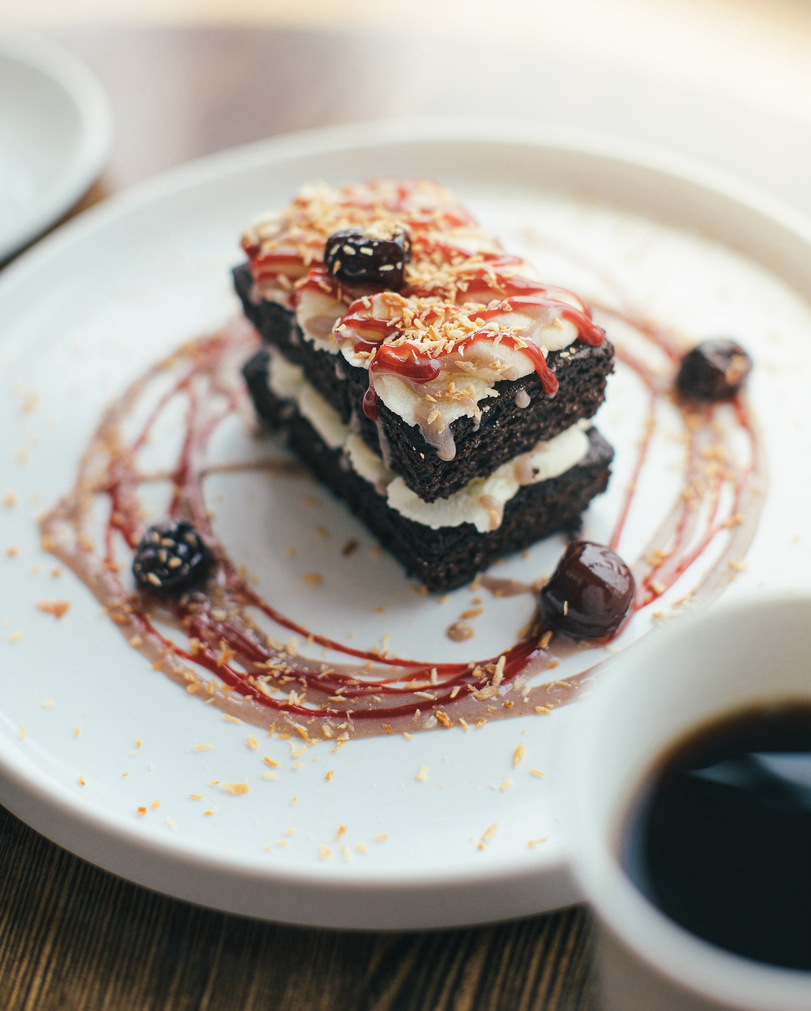 a piece of cake artfully decorated with berries and a circle of drizzled caramel and compote.