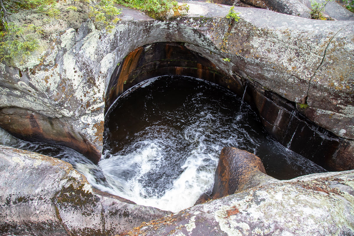 a pothole formation at Potholes Provincial Park; a smooth bowl-like pool cut into a mossy rock face by rushing water. 