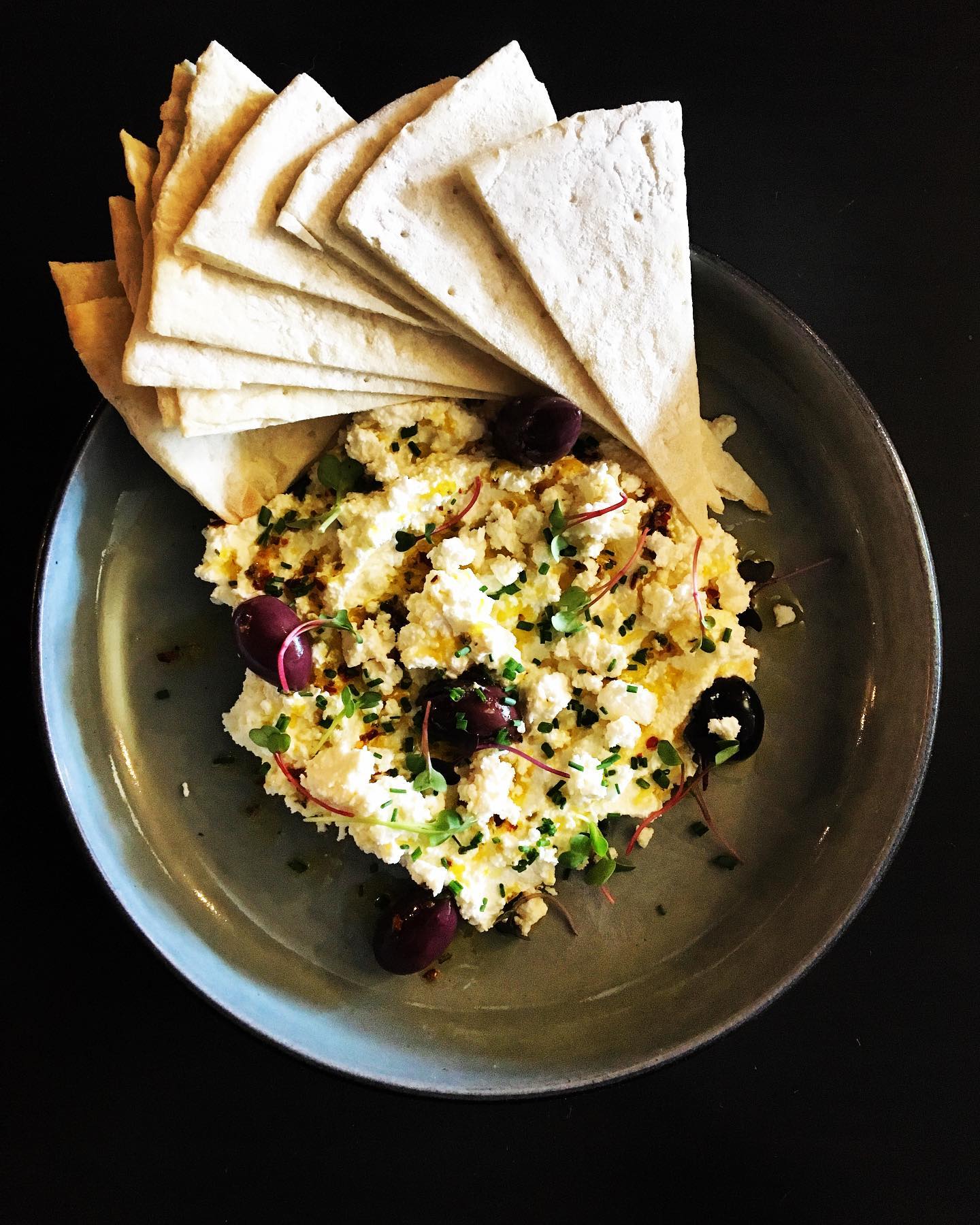 a plate of ricotta and lemon feta with olives and pita