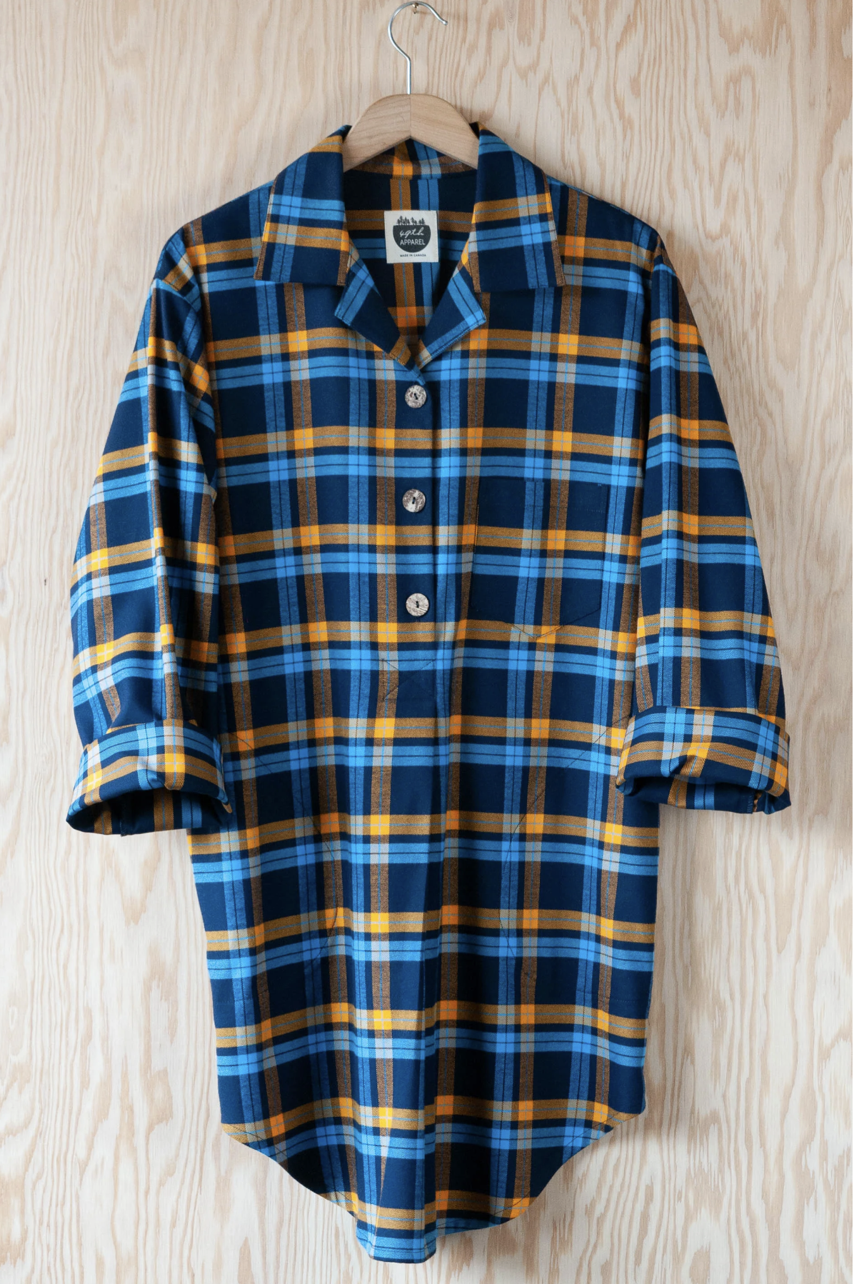 A plaid nightshirt in blue and gold on a hanger.