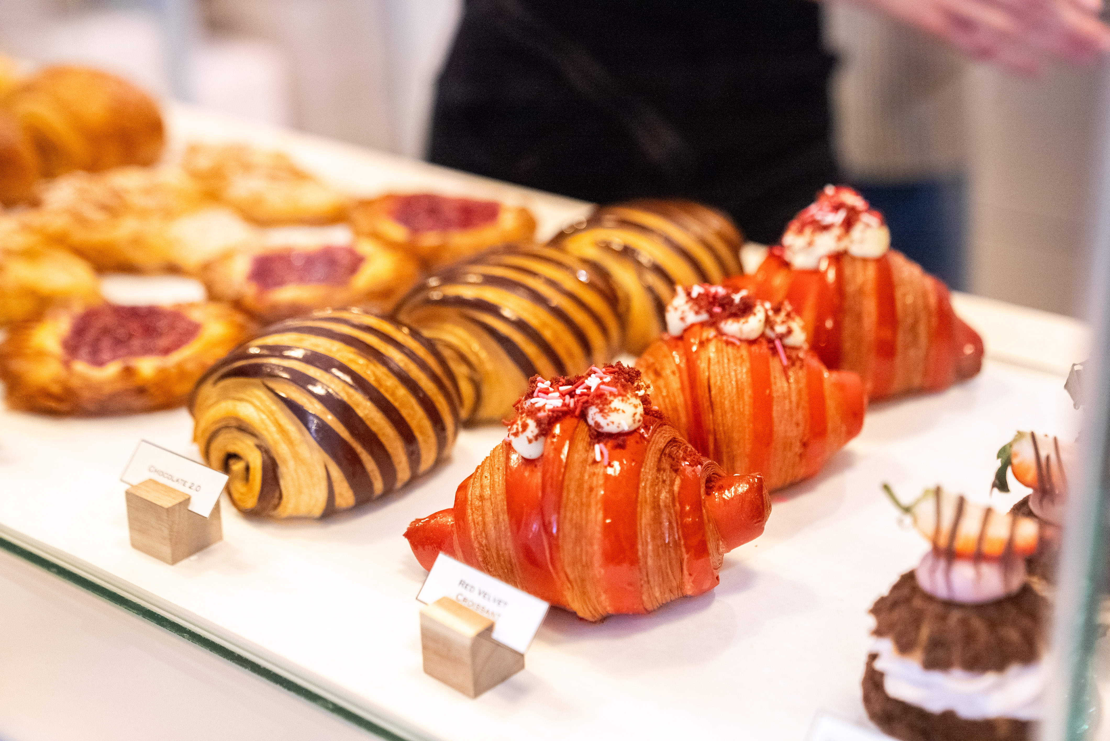 Rows of delicately decorated pastries sitting in a bakery window.