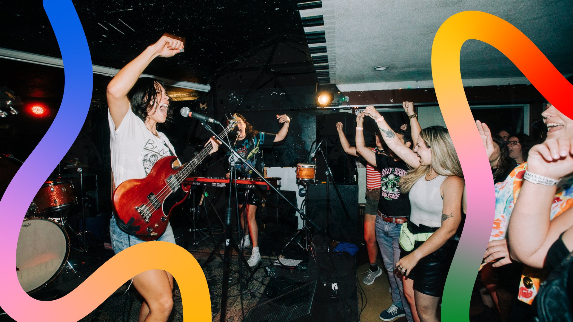 A crowd rocks out to a band playing guitar and instruments on stage.