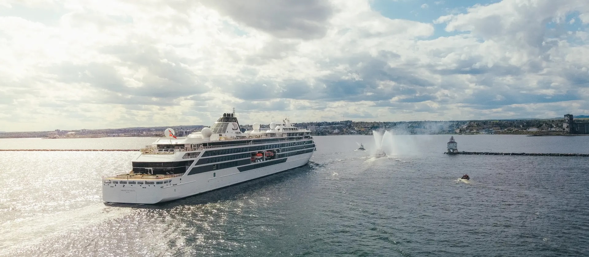 The Viking Octantis, a huge white cruise ship, sails into port under a golden sunset.