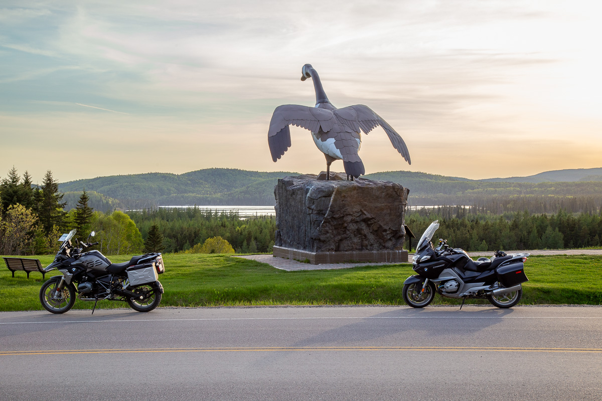 two motorcycles parked next to the Wawa Goose at sunset on a summer day. 