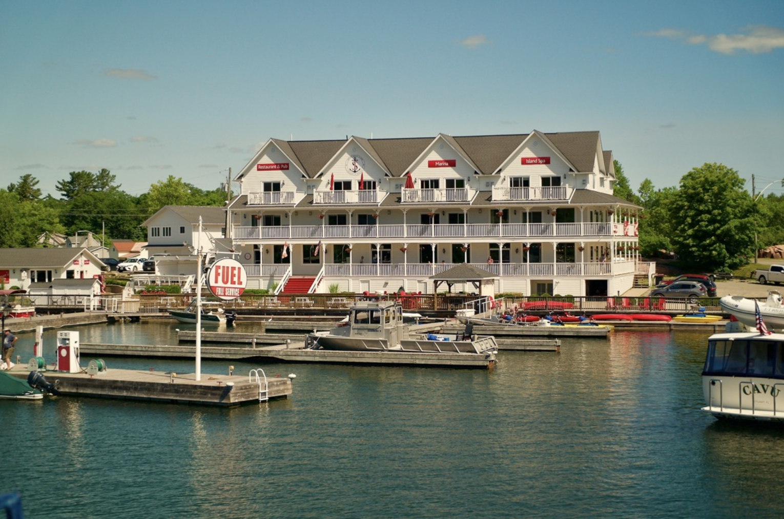 The Sportman's Inn; a large, attractive hotel building surrounded by a pictureque marina and green forested shorline. 