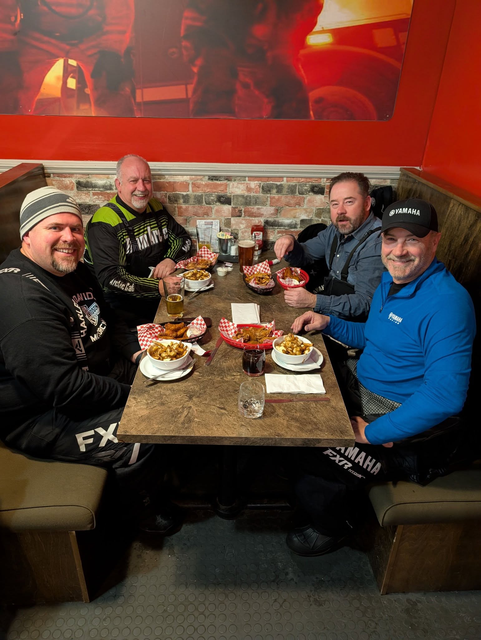 Men eating dinner at a diner table dressed in winter gear.