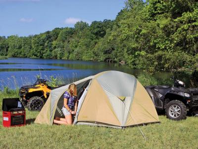 A woman in a tent on a sunny day next to an ATV.