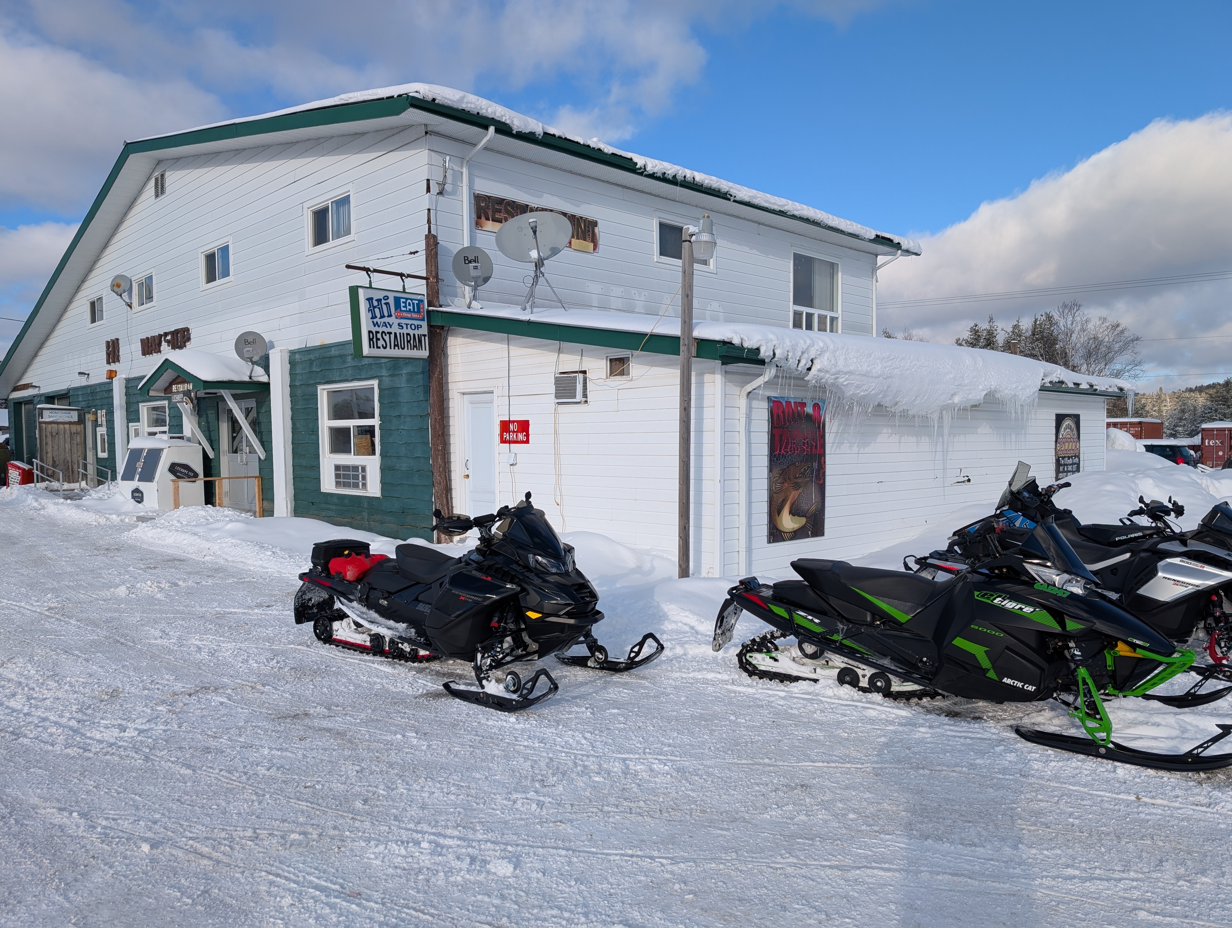 Snowmobile parked in front of a white wooden building.