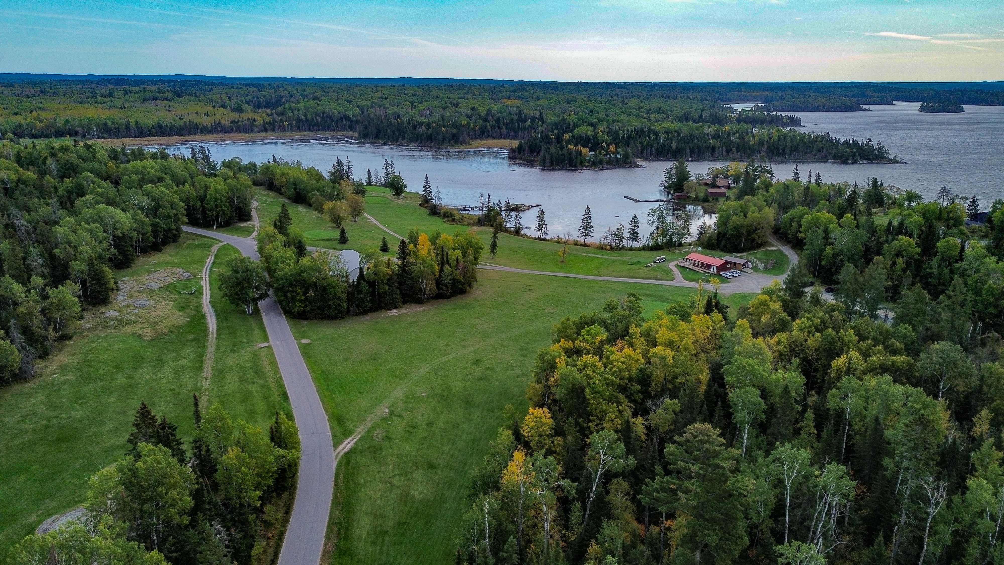 The White Moose Golf Course; a lush green course surrounded by forest next to a shining blue lake.